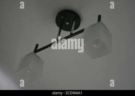 Things, interior items, beautiful chandelier with white matte shades and white diode lamps hangs on the ceiling of room in city Dnipro, Ukraine. Stock Photo
