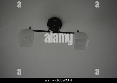 Things, interior items, beautiful chandelier with white matte shades and white diode lamps hangs on the ceiling of room in city Dnipro, Ukraine. Stock Photo