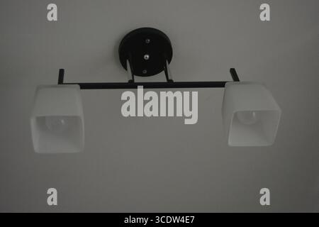 Things, interior items, beautiful chandelier with white matte shades and white diode lamps hangs on the ceiling of room in city Dnipro, Ukraine. Stock Photo