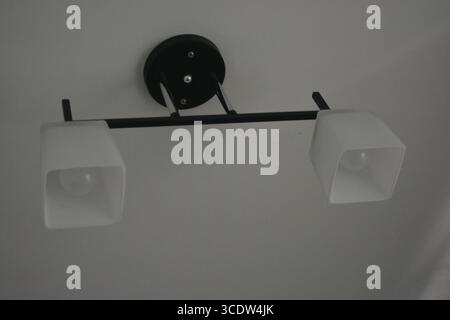 Things, interior items, beautiful chandelier with white matte shades and white diode lamps hangs on the ceiling of room in city Dnipro, Ukraine. Stock Photo