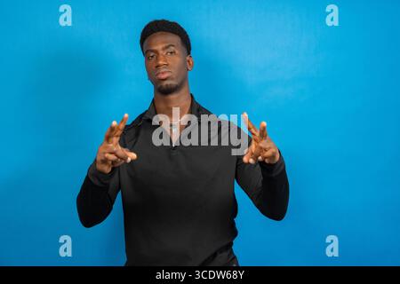 Young man showing peace sign with both hands on blue background Stock Photo
