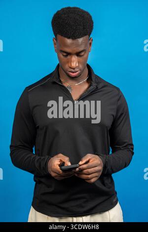 Focused young man using smartphone, browsing internet, chatting online, or playing mobile game Stock Photo