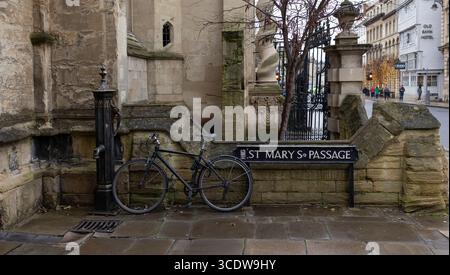 Oxford, united kingdom, 19 December 2023 Black Bicycle Locked Near Historical Building Corner on Wet City Street Stock Photo