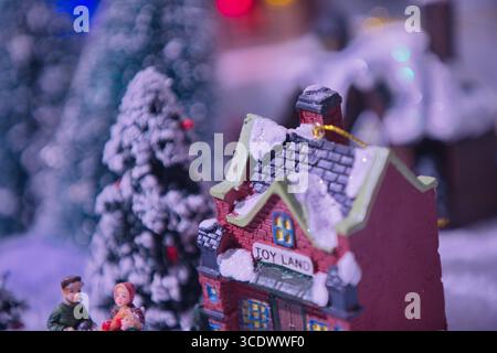 Miniature winter village with a snow-covered toy house and tiny figurines among frosted trees and soft bokeh, in the General Photography Collection. Stock Photo