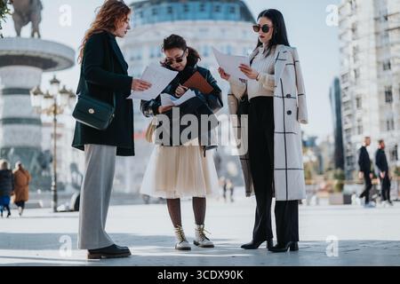 Three businesswomen collaborating outdoors on a project in an urban setting Stock Photo