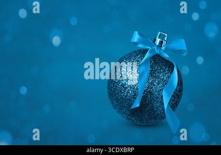 Blue shiny glittery Christmas ornament on blue background with copy space Stock Photo