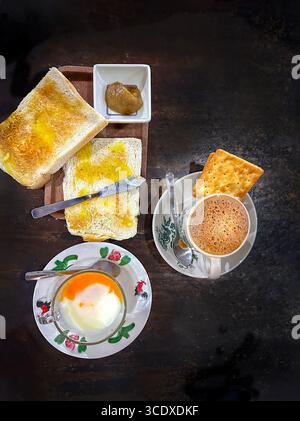 Traditional malaysian breakfast, toast, kaya jam, boiled eggs, coffee, crackers on a rustic surface in a kopitiam coffee shop kuala lumpur, malaysia Stock Photo