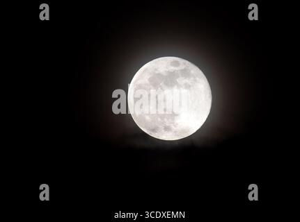 Close-up of a bright full moon against a dark night sky, showing detailed craters and lunar surface textures, captured in high resolution for astronom Stock Photo