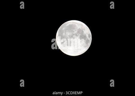 Close-up of a bright full moon against a dark night sky, showing detailed craters and lunar surface textures, captured in high resolution for astronom Stock Photo