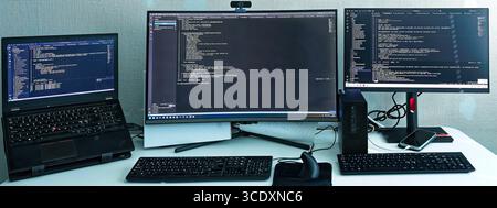 Comprehensive authentic AI developer workspace with development machine and LLM fine-tuning workstation displaying real proprietary code Stock Photo