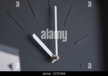 Modern black wall clock with sleek white hands and no numbers Stock Photo