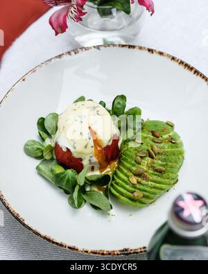 Indulge in the exquisite Gourmet Eggs Benedict with an enticing Avocado Delight that delights Stock Photo