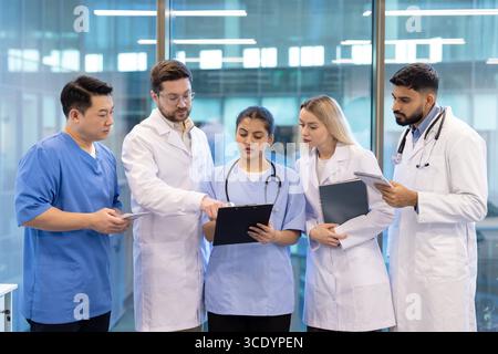 Healthcare team in a professional setting reviewing documents and collaborating on patient diagnostics. Stock Photo