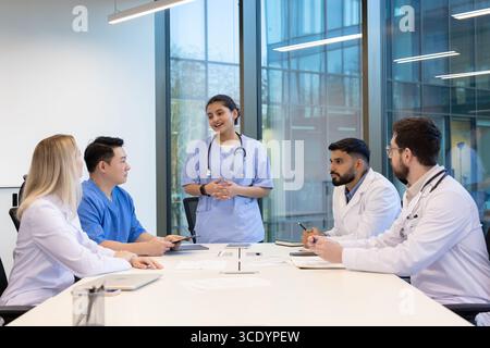 Medical professionals engaging in a collaborative discussion around a table in a modern office environment, showcasing communication, teamwork, and professional exchange. Stock Photo
