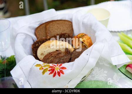 A collection of different bread types displayed in a woven basket lined with a decorative cloth. the scene captures a rustic and inviting table settin Stock Photo