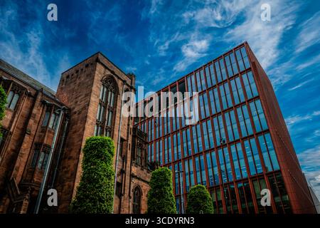 Exterior of John Rylands Research Institute and Library in comparison to modern office blocks, Deansgate Manchester, UK. Stock Photo