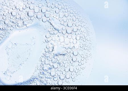 Light blue macro bubbles in transparent liquid texture. Close-up macro shot of oil circles and water bubbles on a light blue abstract background Stock Photo