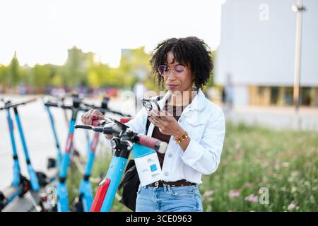 Woman activating electric scooter from smart phone Stock Photo