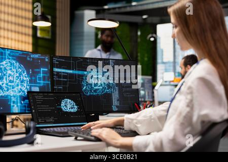 Female engineer developing applications using AI LLM chatbot on multiple devices. Worker doing internship in tech startup relying on artificial intelligence assistant to debug applications Stock Photo