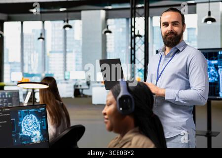 Portrait of team leader supervising programmers at work training deep learning models for anomaly detection. Supervisor overseeing IT workers using artificial intelligence in office to do tasks Stock Photo