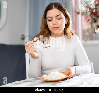 Emotional young woman eating rice at home Stock Photo - Alamy