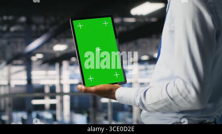 Data center engineers on industrial platform using isolated screen device, collaborating on tasks. Server hub workers visualizing large language model architecture using chroma key tablet Stock Photo