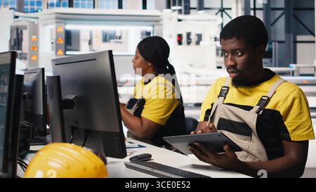 PC based solar technician reviews automation data in production factory, manufacturing industry focused on renewable energy. Worker tracks solar panels and machine performance. Camera B. Stock Photo