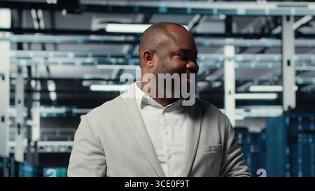 Manager walking in high tech data center facility with multiple rows of fully operational server racks. Supervisor overseeing server hub built for digital storage systems, camera B Stock Photo