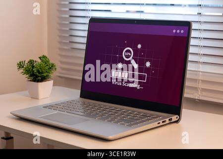 A laptop on the table with virus scanning process. Anti virus and bug protection technology concept. Stock Photo