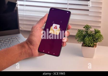 Email or message notification with warning symbol. Man holding a smartphone with email or message spam notification. Stock Photo