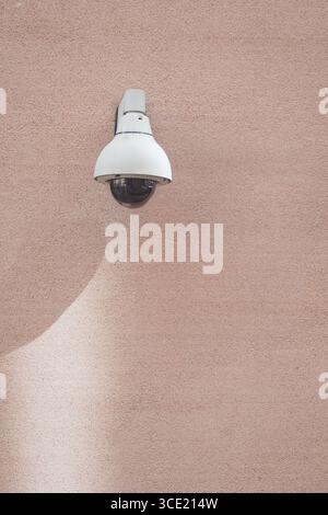 Security camera mounted on a textured pink wall Stock Photo