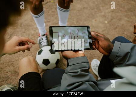 Boys Discussing Soccer Tactics Using Digital Tablet Outdoors Stock Photo