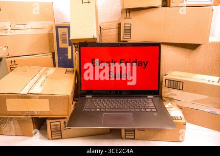 A PC with Black Friday Sale displayed on the screen, sitting in front of a pile of delivered boxes. Stock Photo