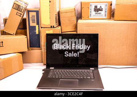 A Black Friday Sale sign with many boxes of received goods behind it. Concept in purchasing items on sale during Black Friday sales. Stock Photo