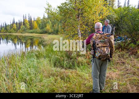 Group of men standing on lakeshore of Miami Lake, Talkeetna Mountains, Matanuska-Susitna, Alaska, USA Stock Photo