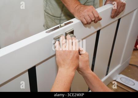 Contractors installing door handle and lock in new white house door Stock Photo