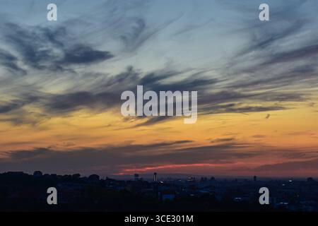 Stunning cityscape at sunset with dramatic, colorful sky and soft gradient clouds. Stock Photo