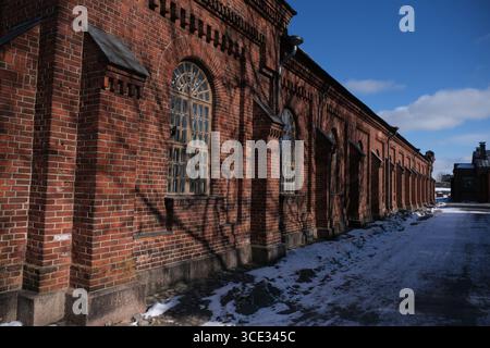 Red brick building side with a big arched window and some snow on the ground. Stock Photo