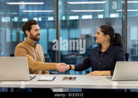Two colleagues engage in a professional handshake, representing partnership and collaboration in business. Stock Photo