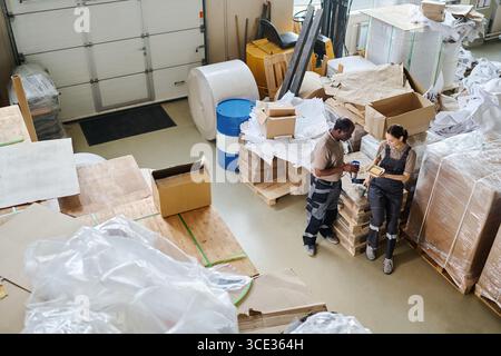 High angle view long shot of two diverse warehouse workers having lunch time, copy space Stock Photo