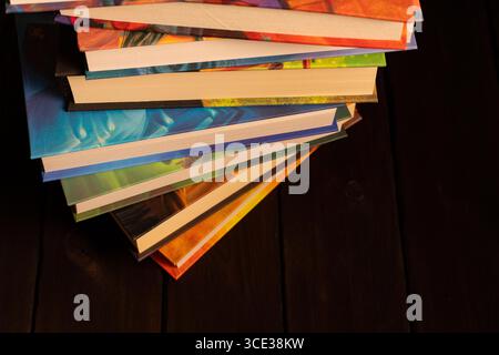 Close-up of a stack of colorful hardcover books on a dark wooden surface. Ideal for educational, literary, or lifestyle-themed projects Stock Photo