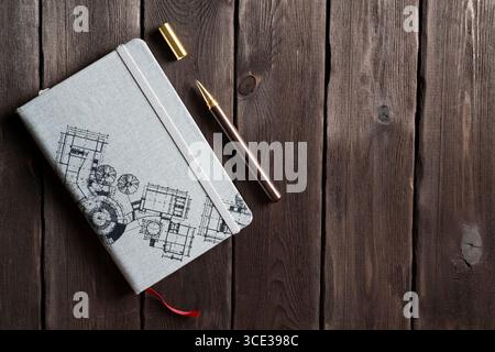 Top view of an architect-themed notebook with a gold-tipped pen placed on a rustic wooden table. Ideal for concepts of architecture, design, creativit Stock Photo
