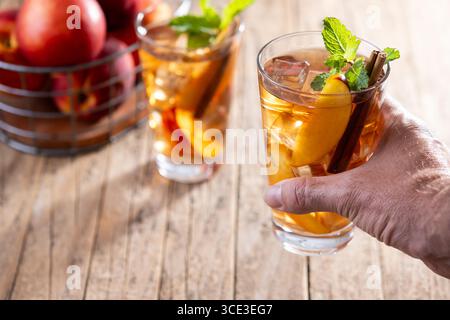 Refreshing peach iced tea in glass with ice cubes on wooden table Stock Photo