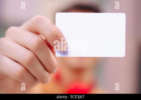 Close-up of hand holding blank white business card with blurred background Stock Photo