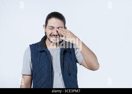 Man suffering from eye allergies on isolated background. Man rubbing his eyes due to allergies. glaucoma concept Stock Photo