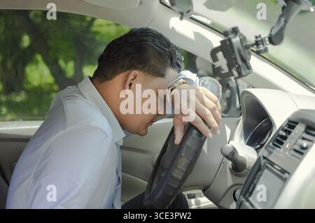 Tired driver leaning on the steering wheel. Tired driver in the car Stock Photo
