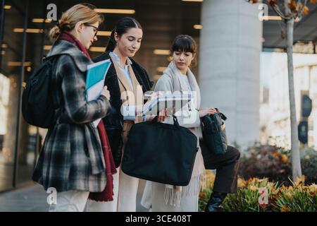 Three Businesswomen Collaborating Together Outdoors in an Urban Setting Stock Photo