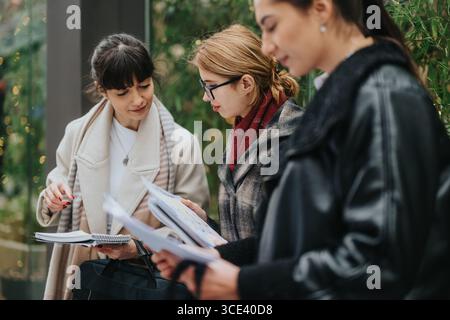 Three professional women discussing documents together outdoors Stock Photo