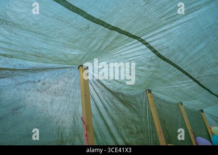 Green tarp rood being supported by wood planks Stock Photo