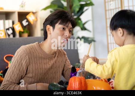Father and Son Enjoying Halloween Crafts. Engaging in creative activities together. Stock Photo
